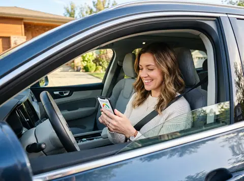 Smiling driver checking her new auto insurance rate on her phone